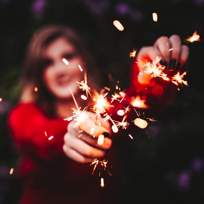 A woman joyfully holds glowing sparklers, embracing a festive moment.